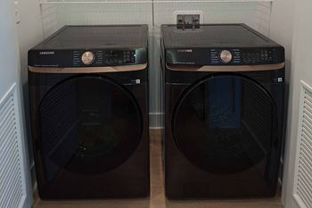 Two Samsung front loading washing machines in a laundry room.